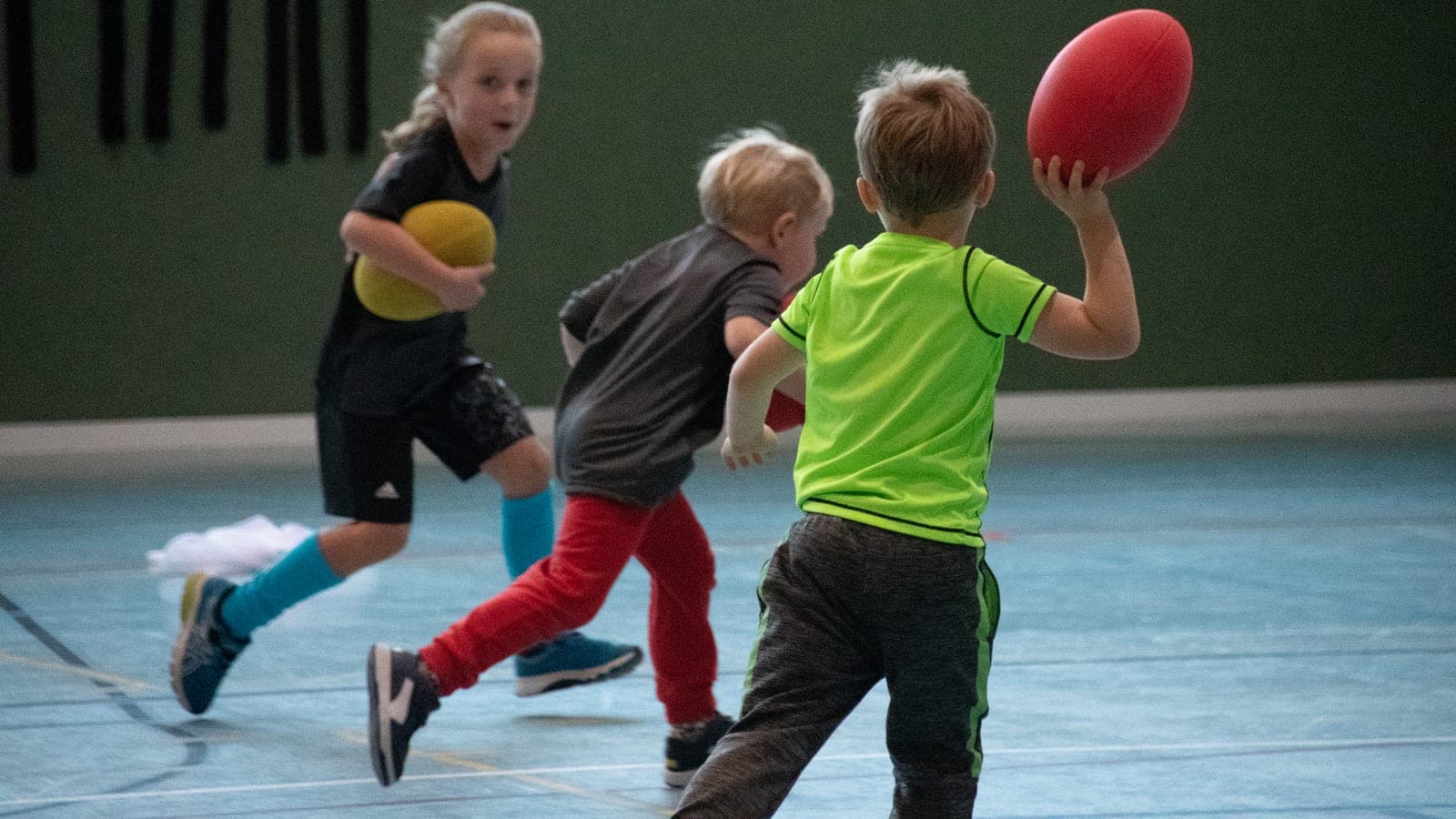 Little Lions coach running a multi-sport session with kids on an indoor court