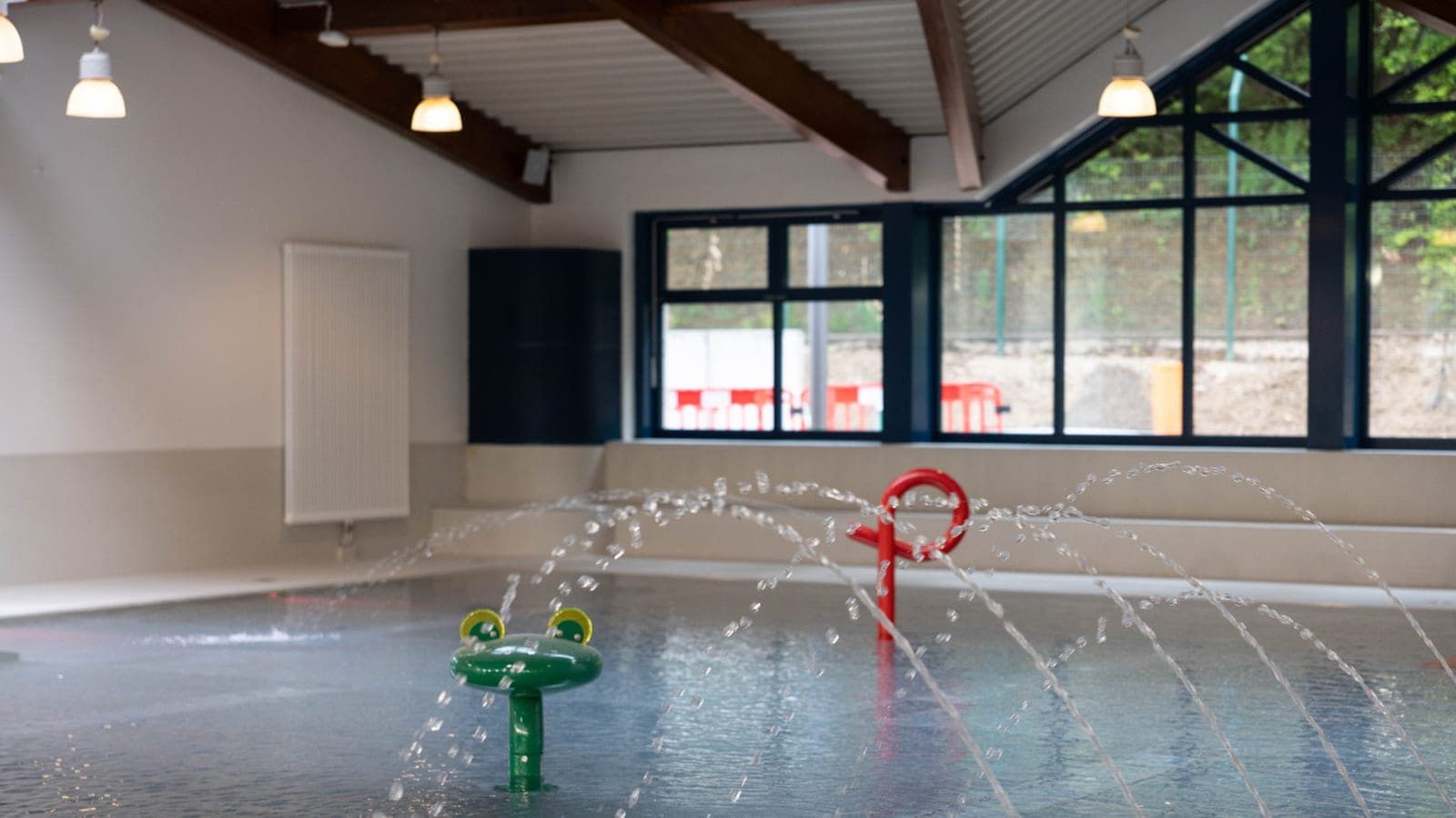 PiKo Piscine Kordall — indoor splash and paddling area with a frog water toy and arcing water jets